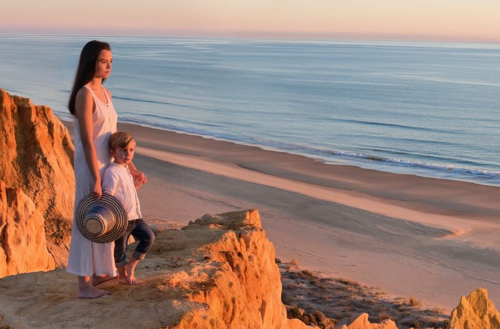 Madre e hijo viendo el atardecer en la playa de Mazagón durante un viaje en familia por la costa de Huelva