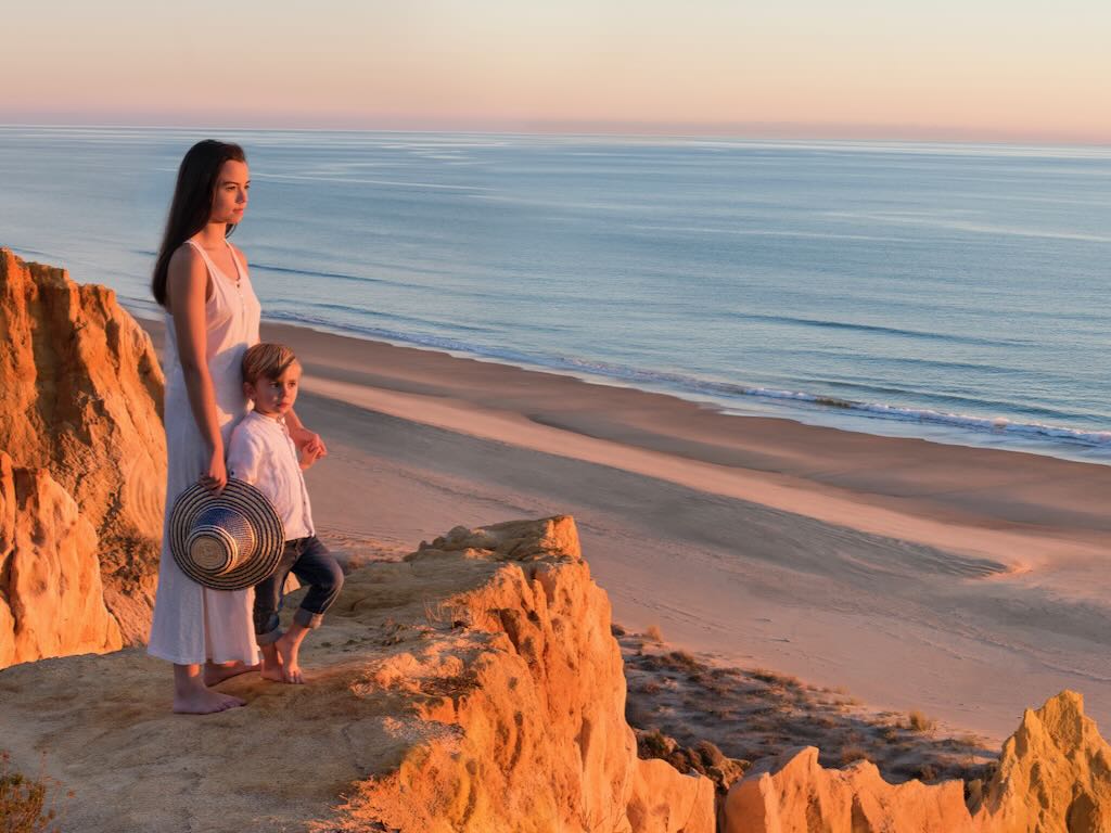 Madre e hijo viendo el atardecer en la playa de Mazagón durante un viaje en familia por la costa de Huelva