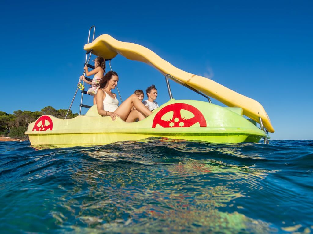 Familia disfrutando de un patín acuático con tobogán en las aguas cristalinas de Cala Martina, Ibiza