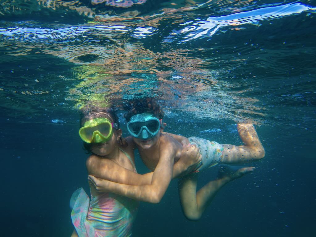 Dos niños haciendo snorkel bajo el agua en las aguas cristalinas de Cala Martina, Ibiza